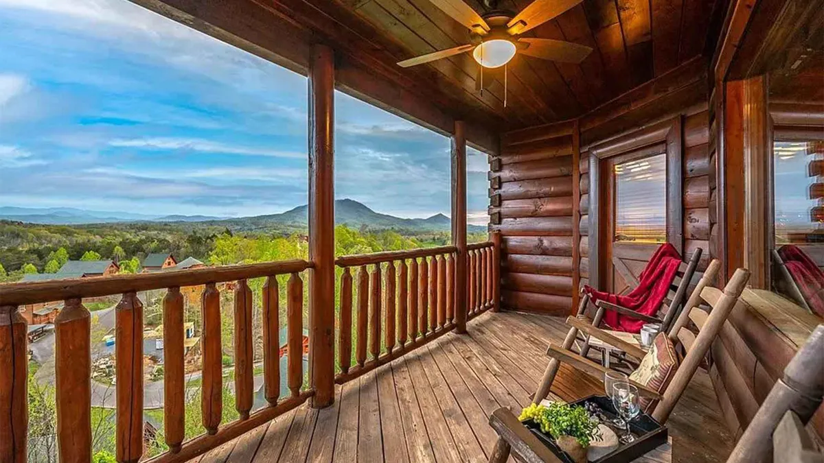 A cozy exterior scene featuring wooden railings, classic rocking chairs, and a panoramic view of the Smoky Mountains. The tranquil setting invites relaxation, conversation, and taking in the evening sky from the cabin’s porch.