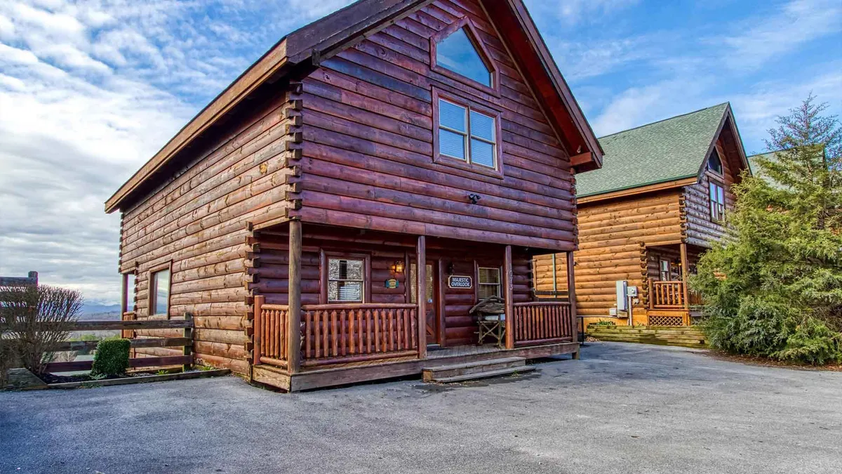 This image features a welcoming log cabin structure with large windows and a spacious front porch set against a backdrop of natural scenery. The porch invites guests to gather, relax, and take in the surrounding wilderness, emphasizing the cabin’s close connection to outdoor adventure.