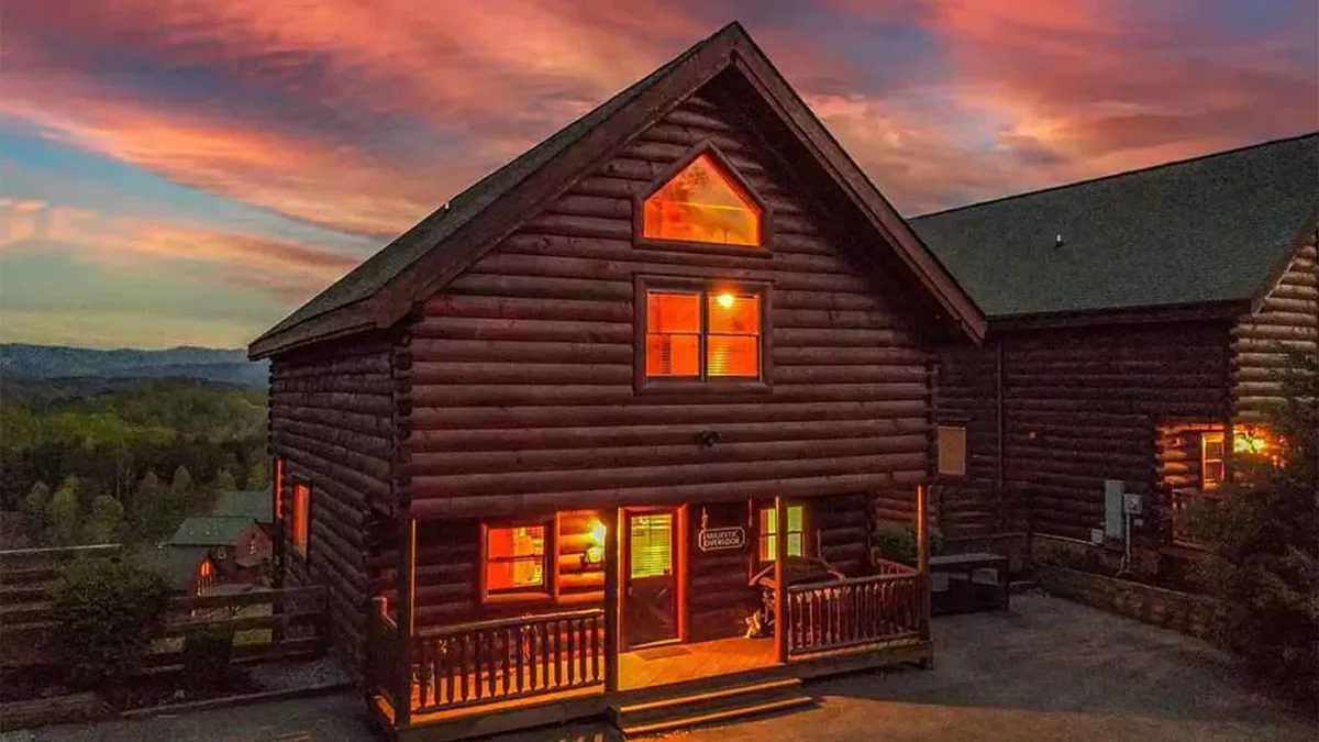 A cozy exterior view of the log cabin at sunset, with warm glowing windows and a peaceful porch. The setting sun creates a magical ambiance, suggesting a perfect end to a day of adventure in the Smokies.